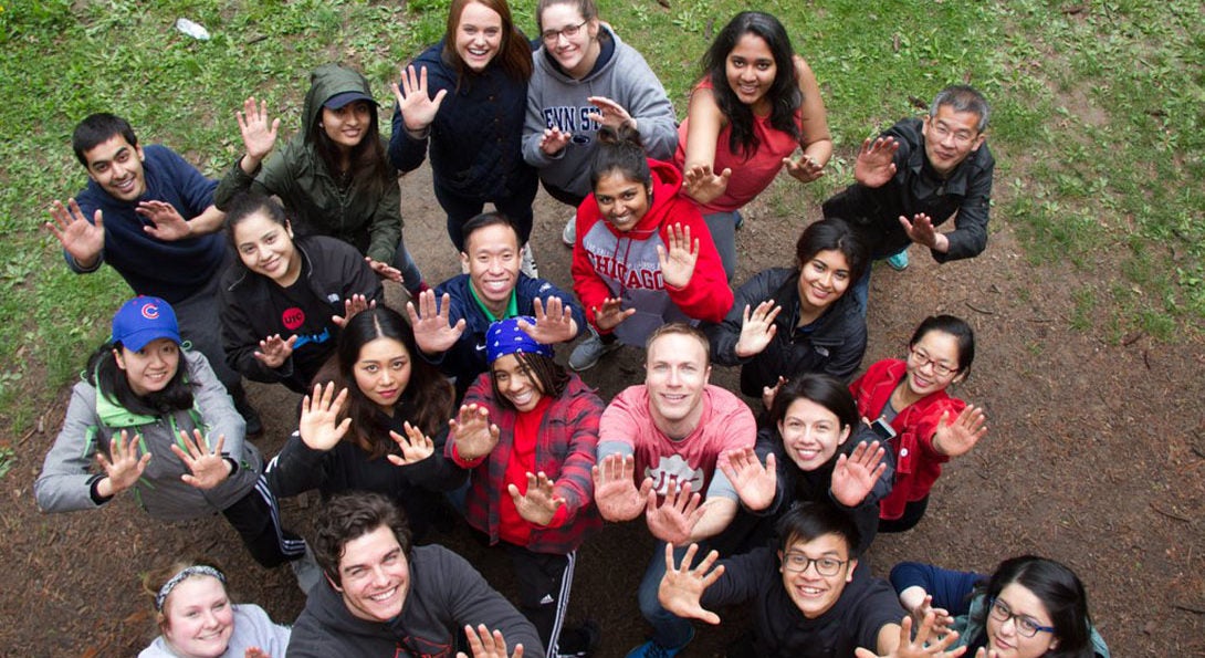 Group of 20 students looking up to camera with arms raised