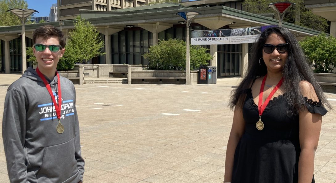 Student Travis Connor Brones on left with leadership certificate medallion around next and student Shraddha Shetty on right with leadership certificate medallion around neck, standing in the quad.