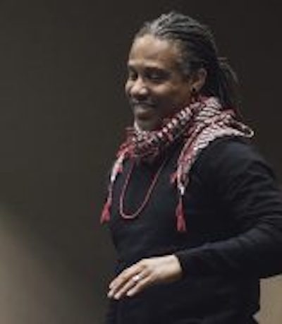 Professor Stovall smiling and looking down in red scarf over black sweater