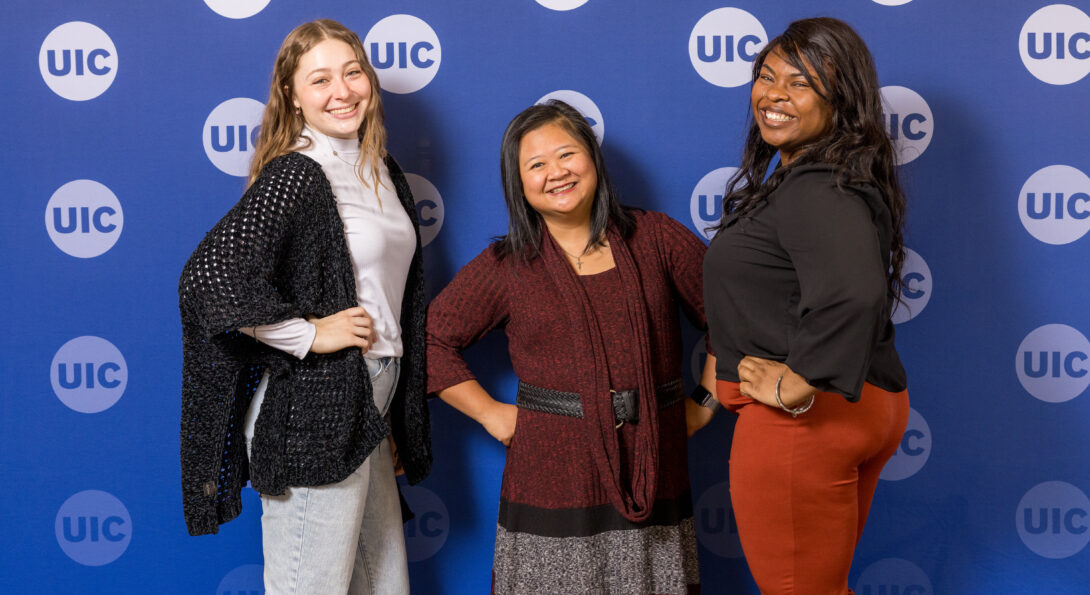 SLCE staff lined up and laughing in staged photo with UIC blue backdrop